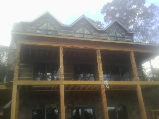 Dormers and porch framing on a large log home under construction — Roof Coating work by our crew in Perryville
