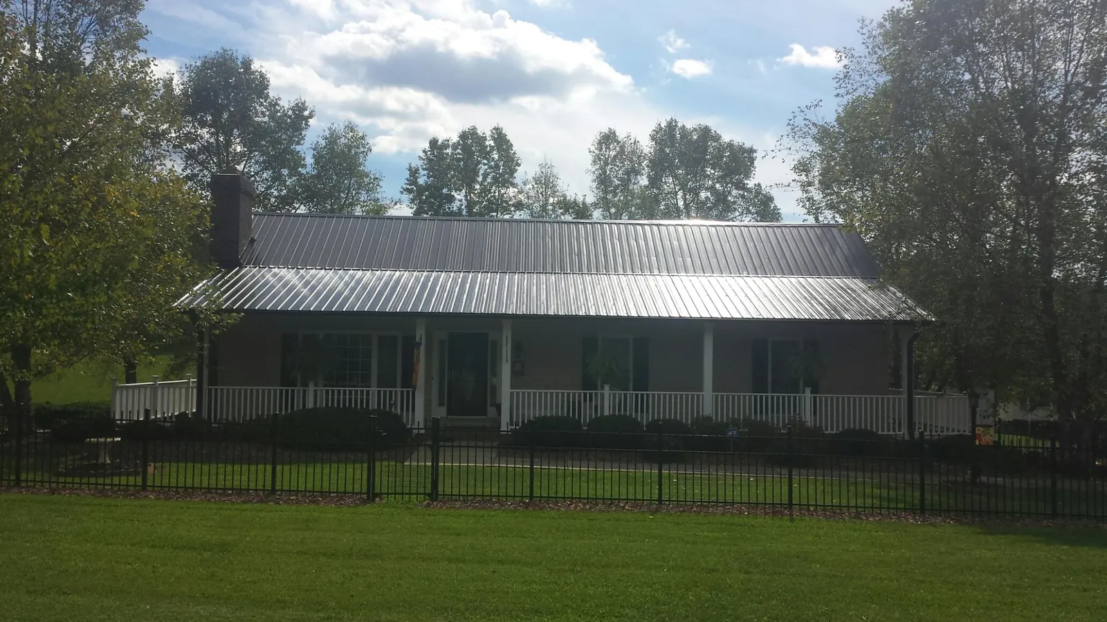 Gray metal roof on a brick ranch with a full width front porch — Gutter Guard Installation work by our crew in Perryville